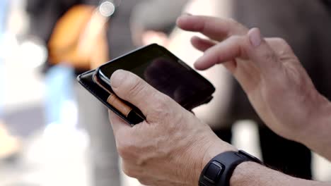 Mature-man's-hands-typing-on-smarphone-in-the-street--devices,communication