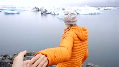 Follow-me-to-concept,-young-woman-leading-boyfriend-to-glacier-lagoon-in-Iceland