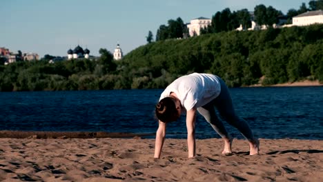 Woman-doing-yoga-on-the-beach-by-the-river-in-the-city.-Beautiful-view-in-Urdhva-Mukha-shvanasana-pose.