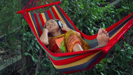 Young-woman-listening-to-music-on-a-hammock.