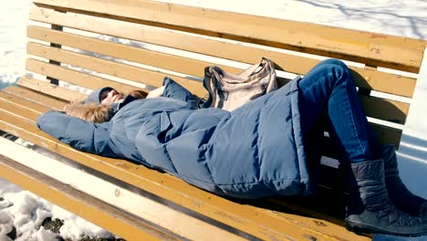 Joven-cansada-se-duerme-en-el-parque-en-un-banco-en-el-invierno.