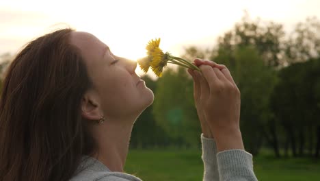 Woman-smells-field-flowers,-face-and-dandelions-close-up