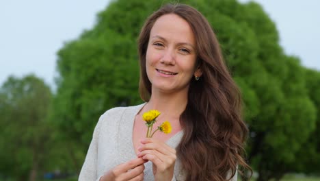 Smiling-woman-with-small-dandelions-in-hands