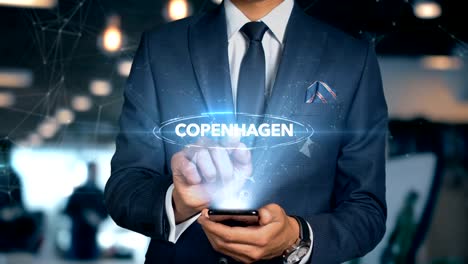 Empresario-con-el-teléfono-móvil-abre-interfaz-de-HUD-de-holograma-y-toques-palabra-país-Copenhague---Capital-