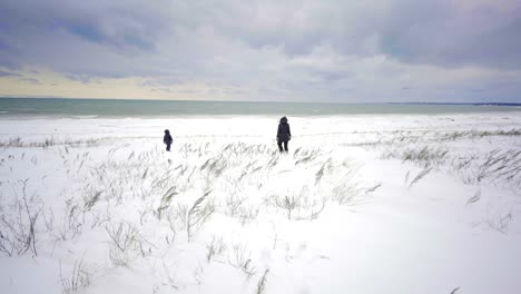 mother-and-kid-walking-on-beach-ontario-canada-in-winter-with-snow