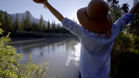 Young-woman-practicing-breathing-exercise-by-the-river-surrounded-by-nature