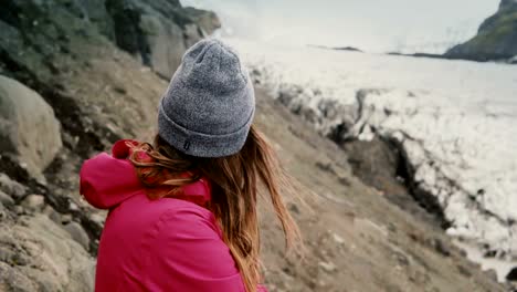 Young-brunette-woman-standing-on-the-mountain-and-looking-on-glaciers-in-Vatnajokull-ice-lagoon-in-Iceland