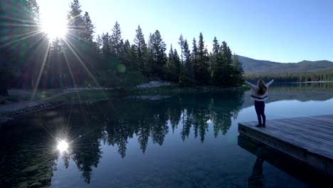 Woman-arms-outreached-by-alpine-lake-in-the-Canadians-rockies