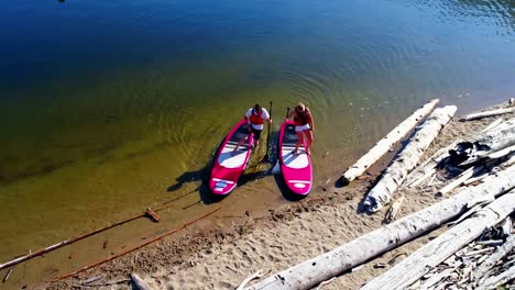 Couple-parking-paddleboard-at-riverbank-on-a-sunny-day-4k