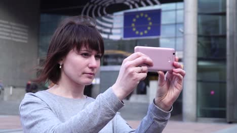 Frau-Tourist-nimmt-Pictureson-auf-Smartphone-in-der-Nähe-des-Europäischen-Parlaments-in-Brüssel.-Belgien