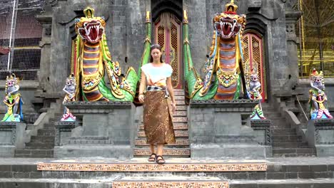 A-woman-descends-the-stone-staircase-with-statues-in-a-Buddhist-temple