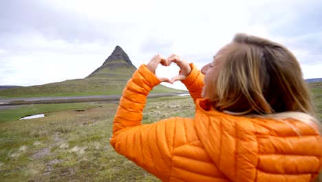 Mujer-joven-en-Islandia-que-marco-del-dedo-corazón-forma-a-la-famosa-montaña-de-Kirkjufell