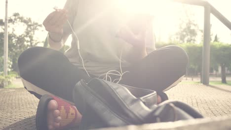 Schöne-junge-asiatische-Frau-anhören-von-Musik-auf-einem-Smartphone-in-der-Stadt.-Junge-asiatische-Frau,-entspannende-Musik-hören-auf-der-Straße.