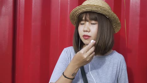 Schöne-junge-asiatische-Frau-anhören-von-Musik-auf-einem-Smartphone-in-der-Stadt.-Junge-asiatische-Frau,-entspannende-Musik-hören-auf-der-Straße.