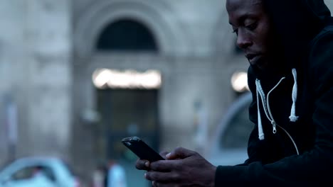 Young-black-american-man-focused-on-typing-on-his-smartphone-in-the-city-profile