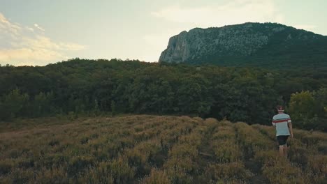 young-man-in-casual-walking-on-a-mountain-field-in-the-evening-during-summer-season