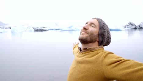 Hombre-joven-de-brazos-extendidos-en-la-laguna-de-glaciar-en-Islandia