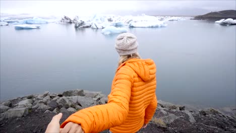 Follow-me-to-concept,-young-woman-leading-boyfriend-to-glacier-lagoon-in-Iceland