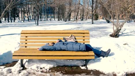 Müde-Mädchen-schläft-im-Park-auf-einer-Bank-im-Winter.