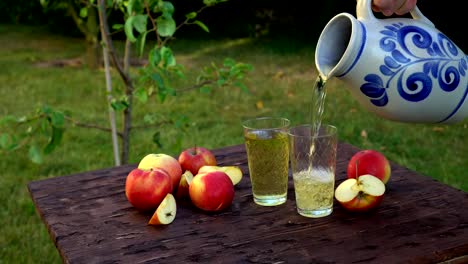 Traditional-apple-wine-in-the-city-of-Frankfurt-in-Hesse.-A-jug-of-wine-is-on-an-old-wooden-table-in-the-garden,-around-it-are-apples