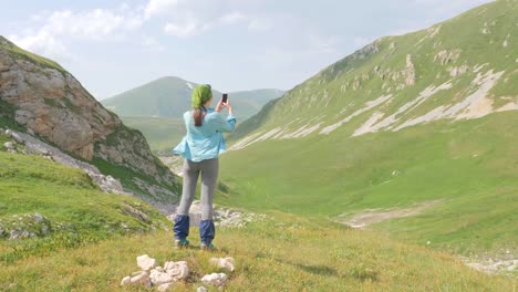 Mujer-caminante-disfrutar-de-hermoso-paisaje-de-montaña-y-hacer-foto-a-teléfono-móvil