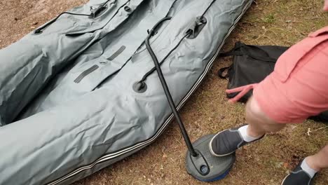 Man-inflating-rubber-boat-for-fishing-by-his-leg-on-the-shore.