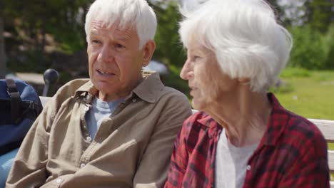 Senior-pareja-hablando-en-el-Banco-durante-la-caminata