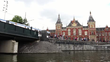 Straßenbahn-Zug-vorbeifährt-Central-Railway-Station-im-Zentrum-von-Amsterdam,-Europa.