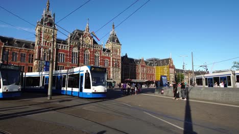 Tram-commuter-train-departs-Central-Railway-Station-in-downtown-Amsterdam,-Europe.