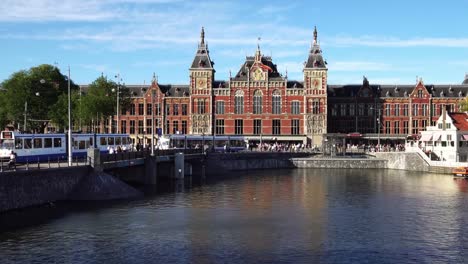 Tram-train-departs-Central-Railway-Station-in-downtown-Amsterdam,-Europe.