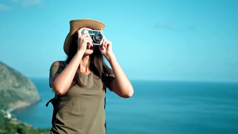 Female-professional-photographer-taking-picture-using-vintage-film-camera-on-peak-of-mountain