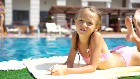 Hermosa-niña-te-diviertes-junto-a-la-piscina-al-aire-libre