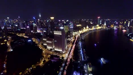 Toma-aérea-de-nave-corriendo-en-el-río-Huangpu-en-la-noche-de-Shanghai,-China