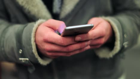 Commuter-person-holding-cellphone-device-browsing-the-internet-on-smartphone-checking-emails-texting-friends-while-on-underground-subway-platform-in-4K