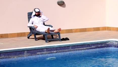 saudi-arabischer-Mann-redet-mit-Handy-am-Swimmingpool