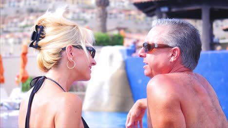 Close-up-of-an-older-couple-sitting-by-a-pool