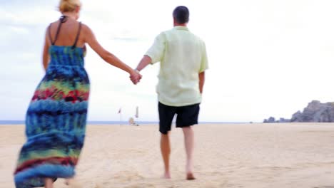 Una-Pareja-de-ancianos-sosteniendo-las-manos-y-caminar-en-la-playa