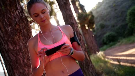 Cross-country-runner-on-a-nature-trail-with-her-smartphone