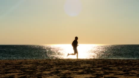 männlichläufer-läuft-am-Strand,-Sonnenuntergang-Silhouette,-Zeitlupe