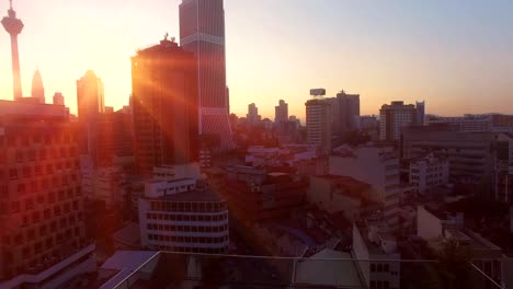 Luftaufnahme-von-Kuala-Lumpur-bei-Sonnenaufgang-mit-der-Sonne-zwischen-des-Kuala-Lumpur-City-Centre-Gebäude