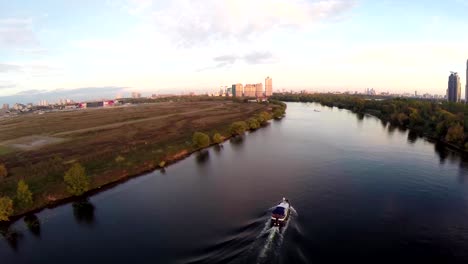 Aerial-shots-of-pleasure-boat-on-the-Moskva-River-at-Strogino-district-of-Moscow,-Russia.-Boat-navigate-on-the-Moscow-river.-Sunrise-sunset.-Alie-parusa-buildings