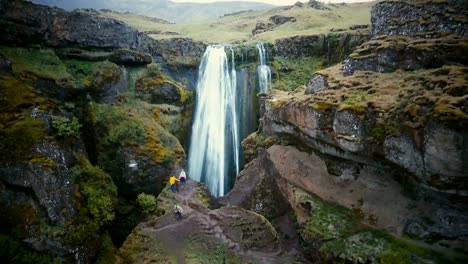 Aerial-view-of-the-tourists-exploring-the-territory-of-Gljufrabui-waterfall-in-Iceland.-Copter-moves-away-from-people