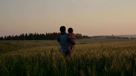 junge-asiatische-Familie-in-einem-Feld-mit-einem-Baby-1-Jahr-auf-der-Hand,-das-Konzept-von-Familienglück,-schöne-Sonne,-Sonnenuntergang,-Slow-motion