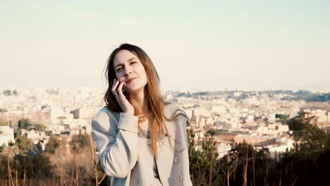 Portrait-of-young-beautiful-woman-standing-on-the-panoramic-view-of-Rome,-Italy.-Female-talking-on-the-smartphone