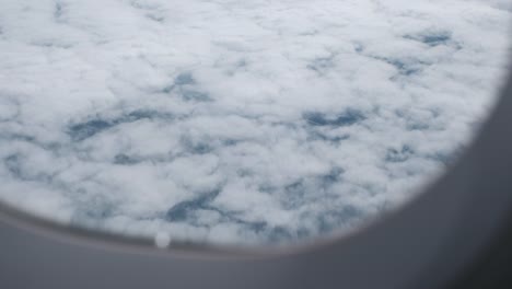 El-cielo-azul-en-un-día-nublado-a-través-de-una-ventana-de-avión