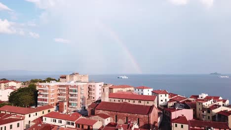 Piombino,-Italia.-Vista-aérea-de-la-ciudad,-mar,-barco-y-arco-iris-en-el-cielo