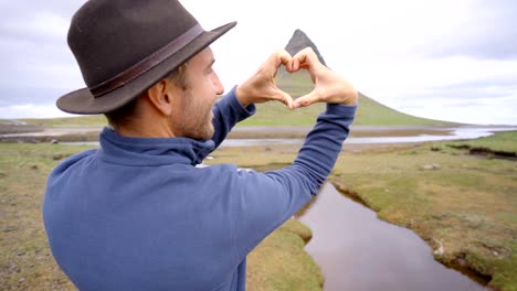 Hombre-joven-en-Islandia-que-marco-del-dedo-corazón-forma-a-la-famosa-montaña-de-Kirkjufell