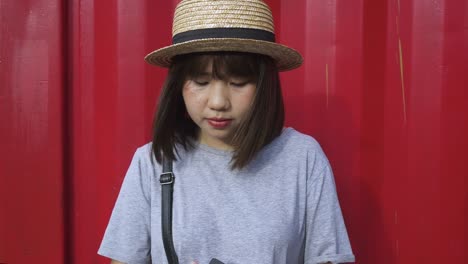 Schöne-junge-asiatische-Frau-anhören-von-Musik-auf-einem-Smartphone-in-der-Stadt.-Junge-asiatische-Frau,-entspannende-Musik-hören-auf-der-Straße.