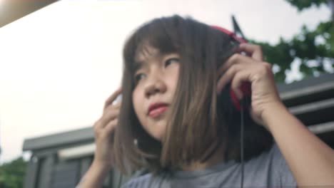 Hermosa-mujer-asiática-joven-escuchando-música-en-un-teléfono-inteligente-en-la-ciudad.-Mujer-asiática-joven-relajarse-escuchando-música-en-la-calle.