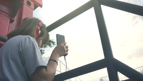 Beautiful-young-asian-woman-listening-to-music-on-a-smart-phone-in-the-city.-Young-asian-woman-relaxing-listening-to-music-on-the-street.